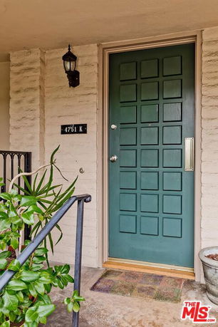 Front view of a house with a green door and decorative light fixture.