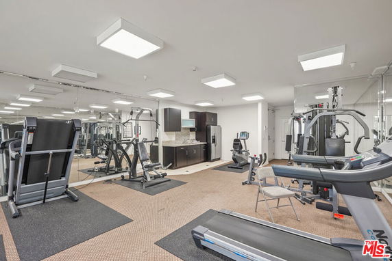 Indoor gym area with various exercise equipment and mirrored walls.
