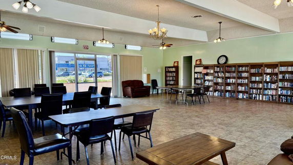 Large indoor room with tables, chairs, and bookshelves.