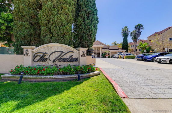 Front view of a building entrance with a sign and trees.