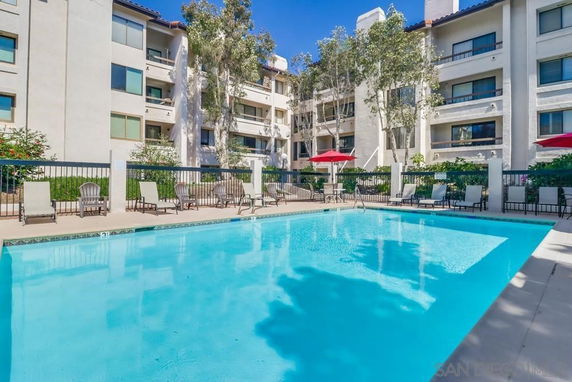 Outdoor swimming pool surrounded by a multi-story building with balconies.