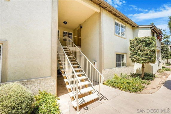 Front view of an apartment building with an exterior staircase leading to the second floor.