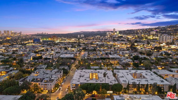 Panoramic view of a cityscape with numerous buildings and lights at dusk.