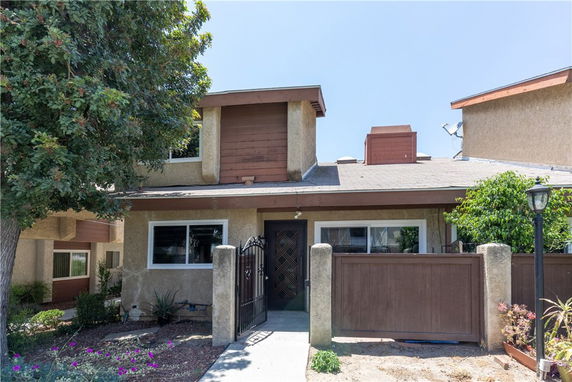 Front view of a two-story townhouse with a gated entrance and a roof with architectural features.