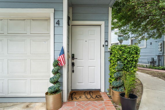 Front view of a house with a white door, garage, and potted plants.