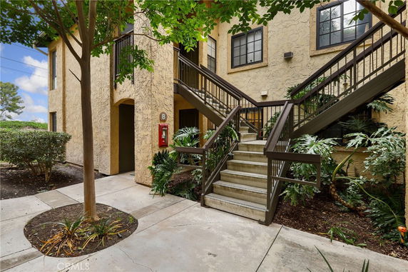 Front view of a multi-story building with external stairs and stucco walls.