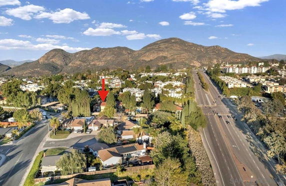 Aerial view of residential neighborhood with houses and a highway in proximity to mountains.