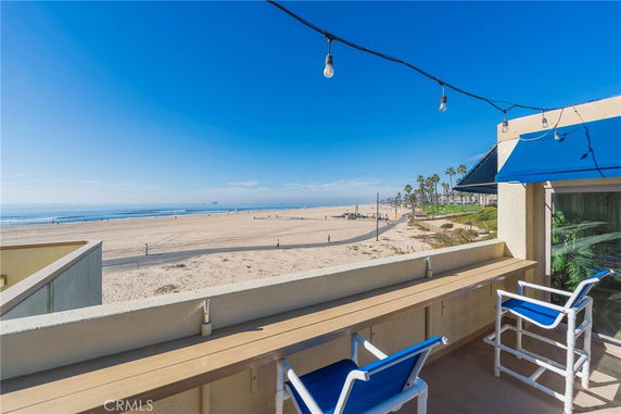Panoramic view from a beachfront building with a patio area overlooking the beach.