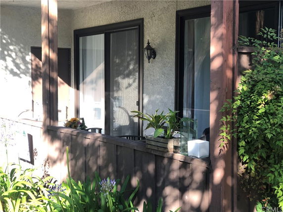 Front view of a house with a small porch and sliding glass doors.