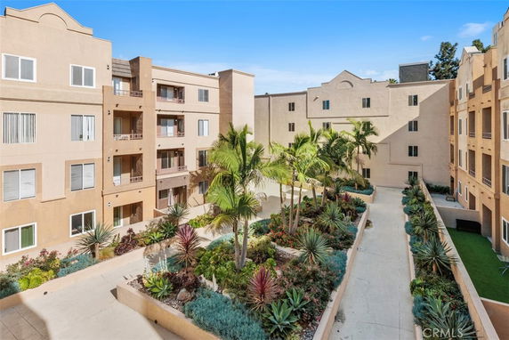 View of a multi-story apartment building with courtyard and plants.