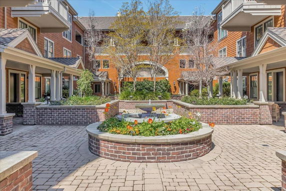 View of a multi-story building with balconies and brick flower bed in a courtyard.