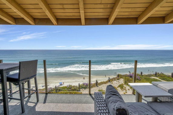 Wide angle view of the ocean from a patio with seating.