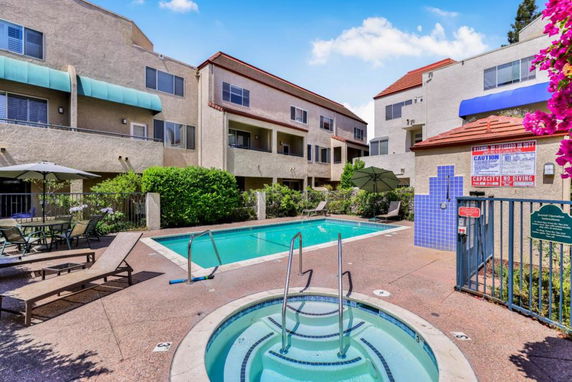 Outdoor view of a swimming pool with a jacuzzi surrounded by residential buildings.