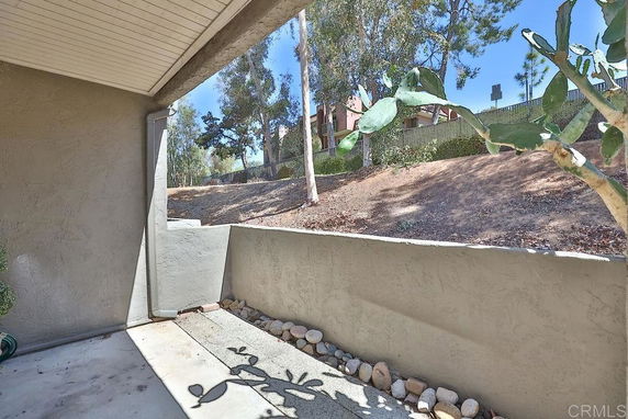Partial view of a covered patio with surrounding trees and shrubs.