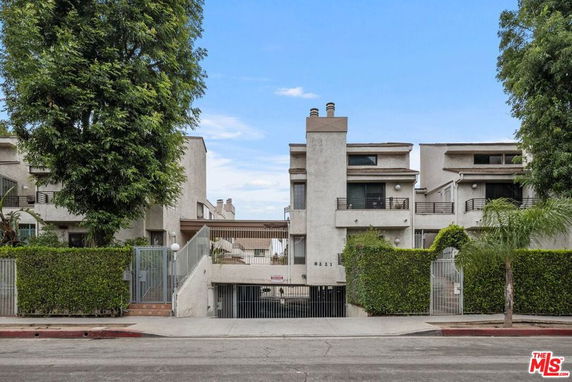 Front view of a multi-story residential building with balconies and a gated entrance.