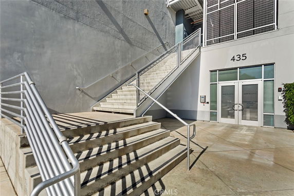 Front view of a building entrance with stairs and metal railings.