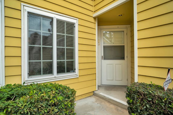 Front view of a house with a yellow exterior and a white door.