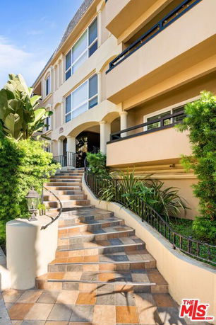Front view of a multi-story building with staircase and plants.