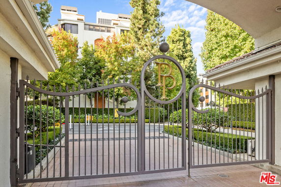 Front view of a building with a decorative iron gate featuring initials.