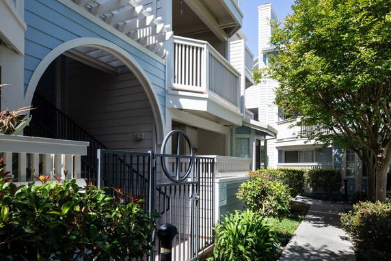 Front view of a multi-story residential building with balconies and a metal gate entrance.