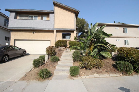 Front view of a two-story house with a garage and steps leading to the entrance.
