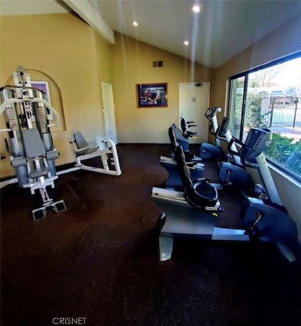 Interior view of a gym area with exercise equipment and large windows.