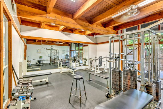 Indoor gym with various exercise equipment and wooden ceiling beams.