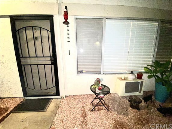 Front view of a house entrance with a metal door, large window, and small outdoor seating area.