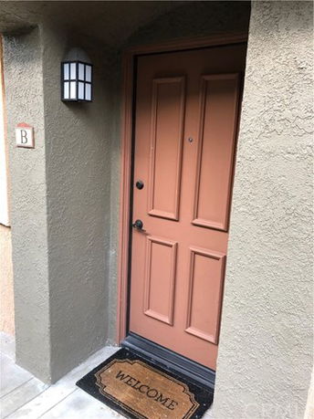 Front view of a house entrance with a brown door and welcome mat.