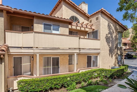 Front view of a two-story house with a balcony and slanted roof.
