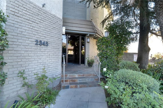Front view of a building entrance with brick facade and glass door.