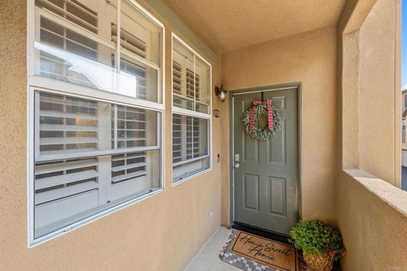 Front entrance of a house with a door decorated with a wreath and a welcome mat.