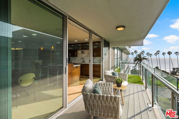 Balcony view with ocean and palm trees in the background.