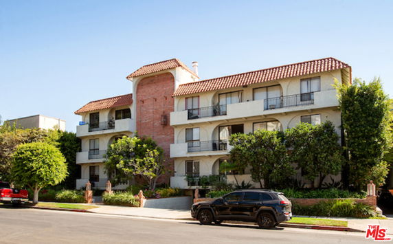 Front view of a multi-story residential building with a brick and stucco exterior and balconies.