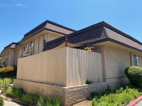 Corner view of a two-story building with a fenced patio area.