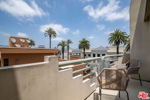 Balcony view overlooking surrounding buildings and palm trees.