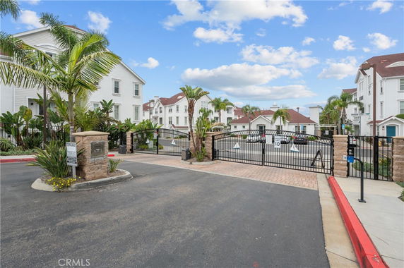 Front view of a gated residential community with multiple buildings featuring white exteriors and red roofs.