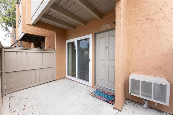 Front view of a building entrance with a small patio area and air conditioning unit.