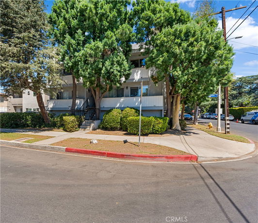 Front view of a two-story building with trees and a sidewalk.