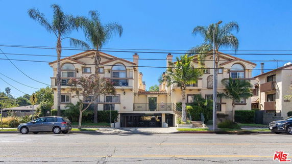 Front view of a multi-story apartment building with balconies and garage access.