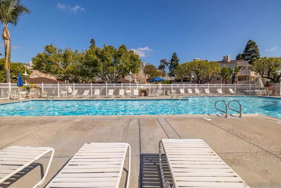 Outdoor swimming pool surrounded by trees and buildings.