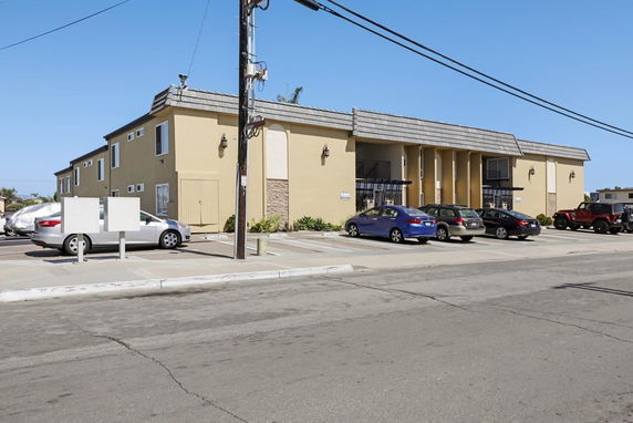 Front view of a two-story building with a parking area in front.