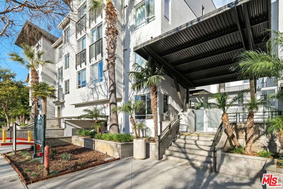 Front view of a multi-story building with a modern design and palm trees.