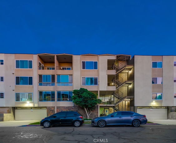 Front view of a multi-story residential building with balconies and parking.