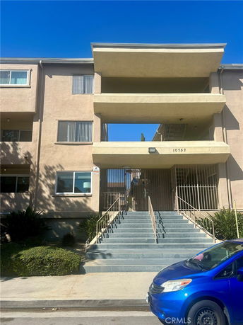 Front view of a multi-story apartment building with staircase entrance.