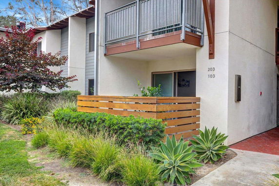 Front view of a multi-story building with a small balcony and a wooden fence.