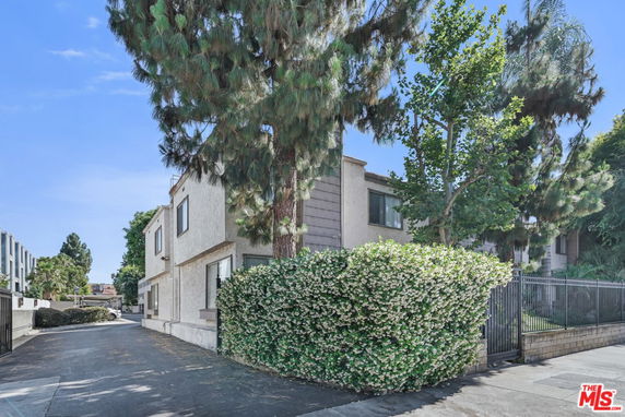 Front view of a two-story house with trees and a gated driveway.