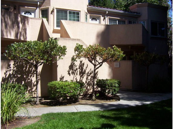 Front view of a two-story building with a stucco exterior and landscaped garden.