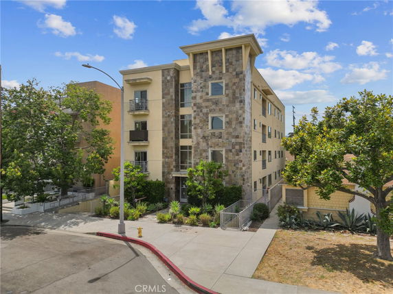 Front view of a multi-story apartment building with stone and stucco exterior.