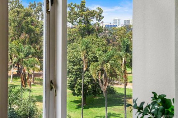 View of surrounding trees and distant buildings from a window.